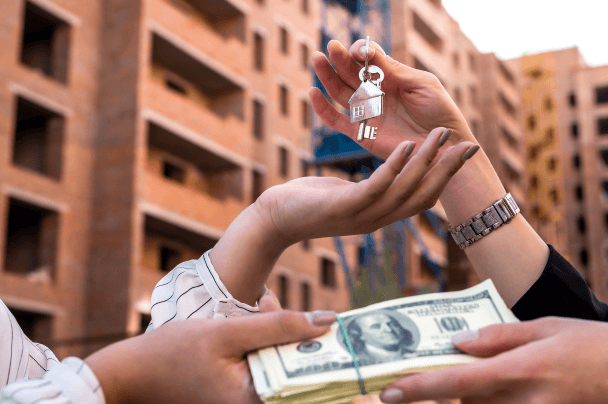 Successful real estate transaction, symbolized by keys being exchanged for money in front of a new building.